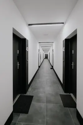 an empty corridor in a building with black doors at Nowy Złocień Comfort Apartment by BookingHost in Kraków
