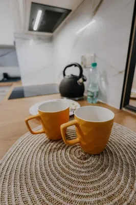 two orange cups sitting on top of a table at Nowy Złocień Comfort Apartment by BookingHost in Kraków