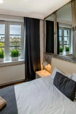 a bedroom with a white bed and two windows at Cracovia Apartments in Kraków