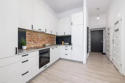 a kitchen with white cabinets and a brick wall at Spacious, 2 Bedrooms Apartment Cracow City Centre by Noclegi Renters in Kraków