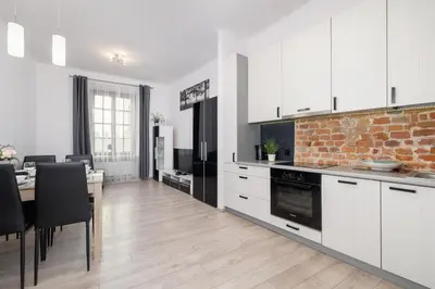 a kitchen with white cabinets and a brick wall at Spacious, 2 Bedrooms Apartment Cracow City Centre by Noclegi Renters in Kraków