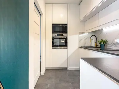 a kitchen with white cabinets and a blue wall at Apartament Filmowej Magii w centrum Krakowa in Kraków