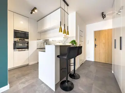 a kitchen with white cabinets and a black stool at Apartament Filmowej Magii w centrum Krakowa in Kraków