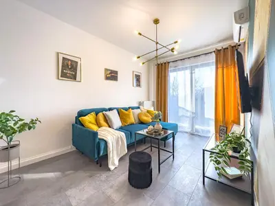a living room with a blue couch and yellow pillows at Apartament Filmowej Magii w centrum Krakowa in Kraków