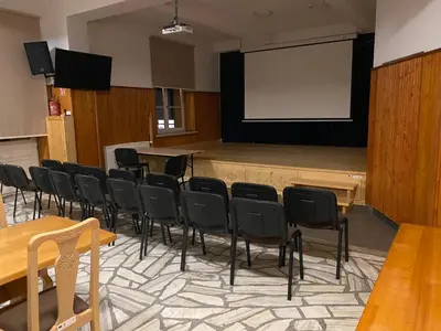 a large room with a stage with chairs and a screen at MODRZEW - noclegi w Pyzówce in PyzÃ³wka