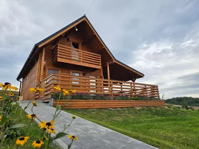 a wooden cabin with a porch and a field of flowers at Sielanka u Basi in Toporzysko