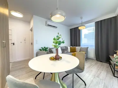 a living room with a white table and chairs at Krakowska Oaza Komfortu - Apartament Premium z Garażem in Kraków