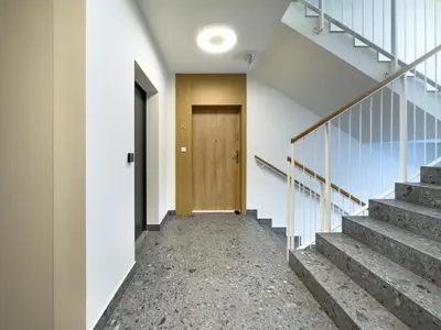 a hallway with stairs and a wooden door at Krakowska Oaza Komfortu - Apartament Premium z Garażem in Kraków