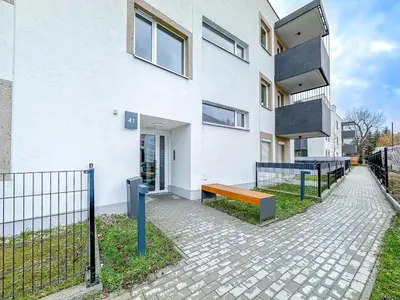 a white building with a bench in front of it at Krakowska Oaza Komfortu - Apartament Premium z Garażem in Kraków