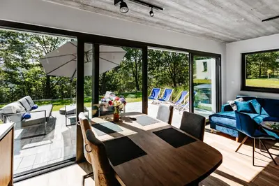 a living room with a wooden table and a large window at Tarnova Chill in Tarnawa