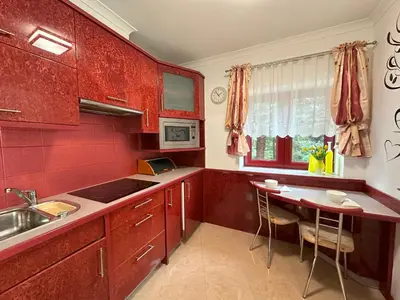 a kitchen with red cabinets and a small table at Apartamenty Pod Dzwonkiem in Wadowice