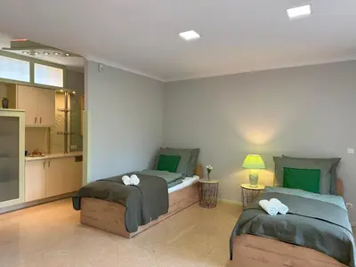 two twin beds in a room with a kitchen at Apartamenty Pod Dzwonkiem in Wadowice
