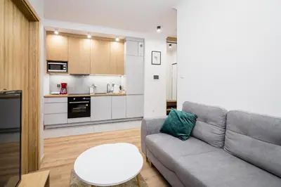 a living room with a couch and a table and a kitchen at Deluxe residence apartment in Kraków