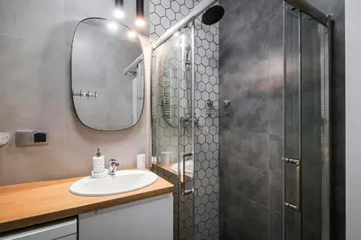 a bathroom with a sink and a shower with a mirror at Deluxe residence apartment in Kraków