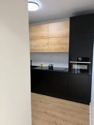 a kitchen with black appliances and wooden cabinets at M&S Apartment in Kraków