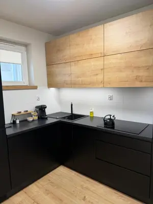 a kitchen with black counters and wooden cabinets at M&S Apartment in Kraków