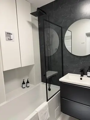 a white bathroom with a shower and a sink at M&S Apartment in Kraków