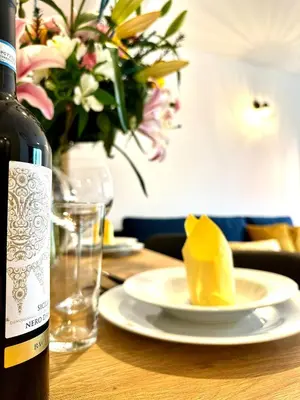 a bottle of wine and a plate of food on a table at COZY OLD-Town Apartments at Kazimierz +AC, KITCHEN and NETFLIX in Kraków