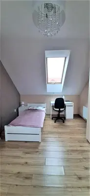 a bedroom with a bed and a chair and a chandelier at House between Cracow and Wieliczka in Wieliczka