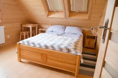 a bedroom with a bed in a wooden cabin at Domek na Zawojskim Przysłopiu in Zawoja
