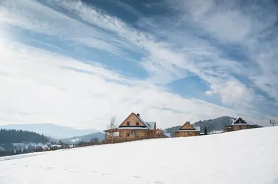 a group of buildings on top of a snow covered hill at Domek na Zawojskim Przysłopiu in Zawoja