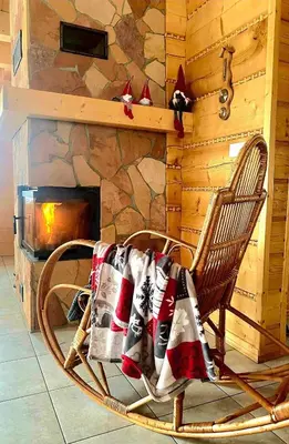 a chair with a blanket on it in front of a fireplace at Domek na Zawojskim Przysłopiu in Zawoja