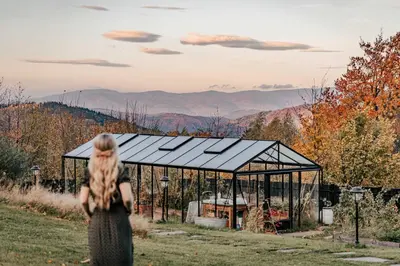 a woman standing in front of a greenhouse at U Pana Boga za piecem - domki w górach, Sauna, Beskidy, Koszarawa in Korbielów