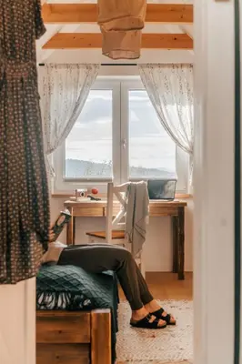 a woman sitting at a desk in a room with a window at U Pana Boga za piecem - domki w górach, Sauna, Beskidy, Koszarawa in Korbielów