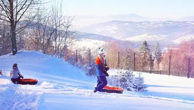a person standing in the snow with a snowboard at U Pana Boga za piecem - domki w górach, Sauna, Beskidy, Koszarawa in Korbielów