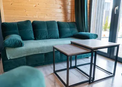 a green couch with two tables in a living room at Widokowe Stodoły balia z hydromasażem na wylączność in Chyszówki