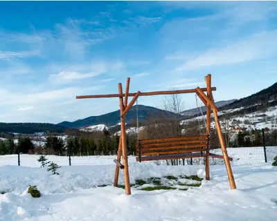 a wooden bench sitting in the snow at Widokowe Stodoły balia z hydromasażem na wylączność in Chyszówki