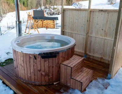 a hot tub on a deck in the snow at Widokowe Stodoły balia z hydromasażem na wylączność in Chyszówki
