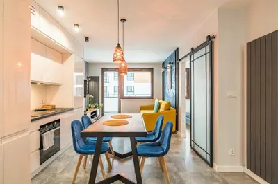 a kitchen and dining room with a table and blue chairs at Tauron Arena Modern Apartment - Parking and Balcony by Rentujemy in Kraków