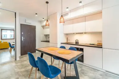 a kitchen with a wooden table and blue chairs at Tauron Arena Modern Apartment - Parking and Balcony by Rentujemy in Kraków