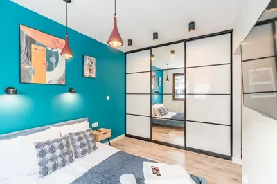 a bedroom with a bed and a blue wall at Tauron Arena Modern Apartment - Parking and Balcony by Rentujemy in Kraków