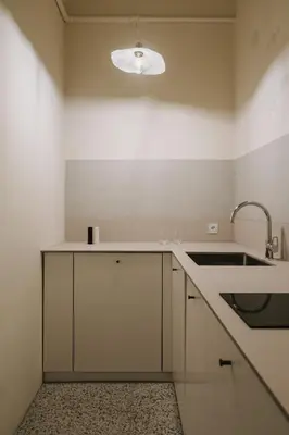 a kitchen with white cabinets and a sink and a light at HERE Apartments in Kraków