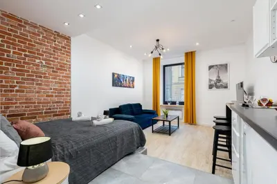 a living room with a bed and a brick wall at Yellow Window Apartment in Kraków