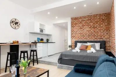 a living room with a bed and a brick wall at Yellow Window Apartment in Kraków