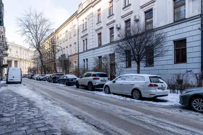 a row of cars parked on a snow covered street at Yellow Window Apartment in Kraków