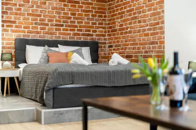 a bed in a room with a brick wall at Yellow Window Apartment in Kraków