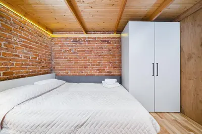 a bedroom with a white bed and a brick wall at Vélo Apartment, High Standard, TV, WiFi in Kraków