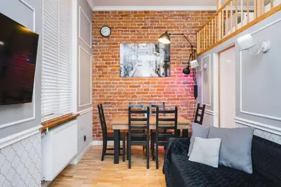 a dining room with a table and a brick wall at Vélo Apartment, High Standard, TV, WiFi in Kraków