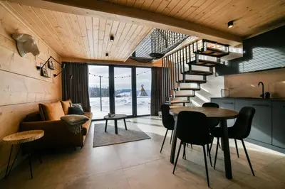 a living room with a staircase and a table and chairs at Bocianie Gniazdo w Rabce in Rabka-Zdroj