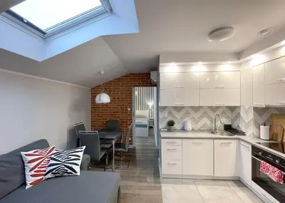 a kitchen with white cabinets and a living room at Z&M apartments - Cracow Old Town in Kraków