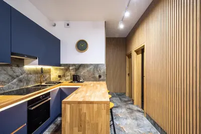 a kitchen with blue cabinets and a wooden counter top at RentPlanet - Apartamenty Kościuszki in Kraków