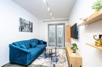 a living room with a blue couch and a table at RentPlanet - Apartamenty Kościuszki in Kraków