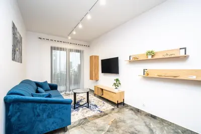 a living room with a blue couch and a tv at RentPlanet - Apartamenty Kościuszki in Kraków