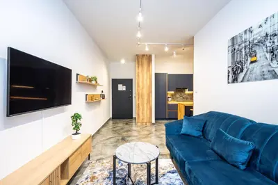 a living room with a blue couch and a tv at RentPlanet - Apartamenty Kościuszki in Kraków