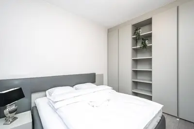 a white bedroom with a bed and a shelf at RentPlanet - Apartament Lubicz in Kraków