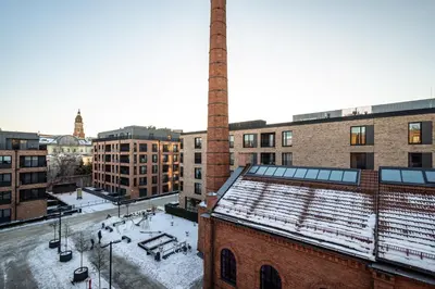 an old factory with a chimney and snow on the roof at RentPlanet - Apartament Lubicz in Kraków